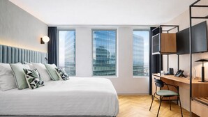 A modern hotel room with a large bed, a desk, and a TV. - H4 Wyndham Paris Pleyel (Saint-Denis)