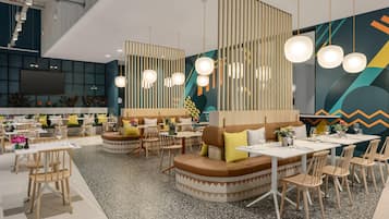 Un intérieur de restaurant moderne, caractérisé par de hauts plafonds, des gradins et un éclairage contemporain.
