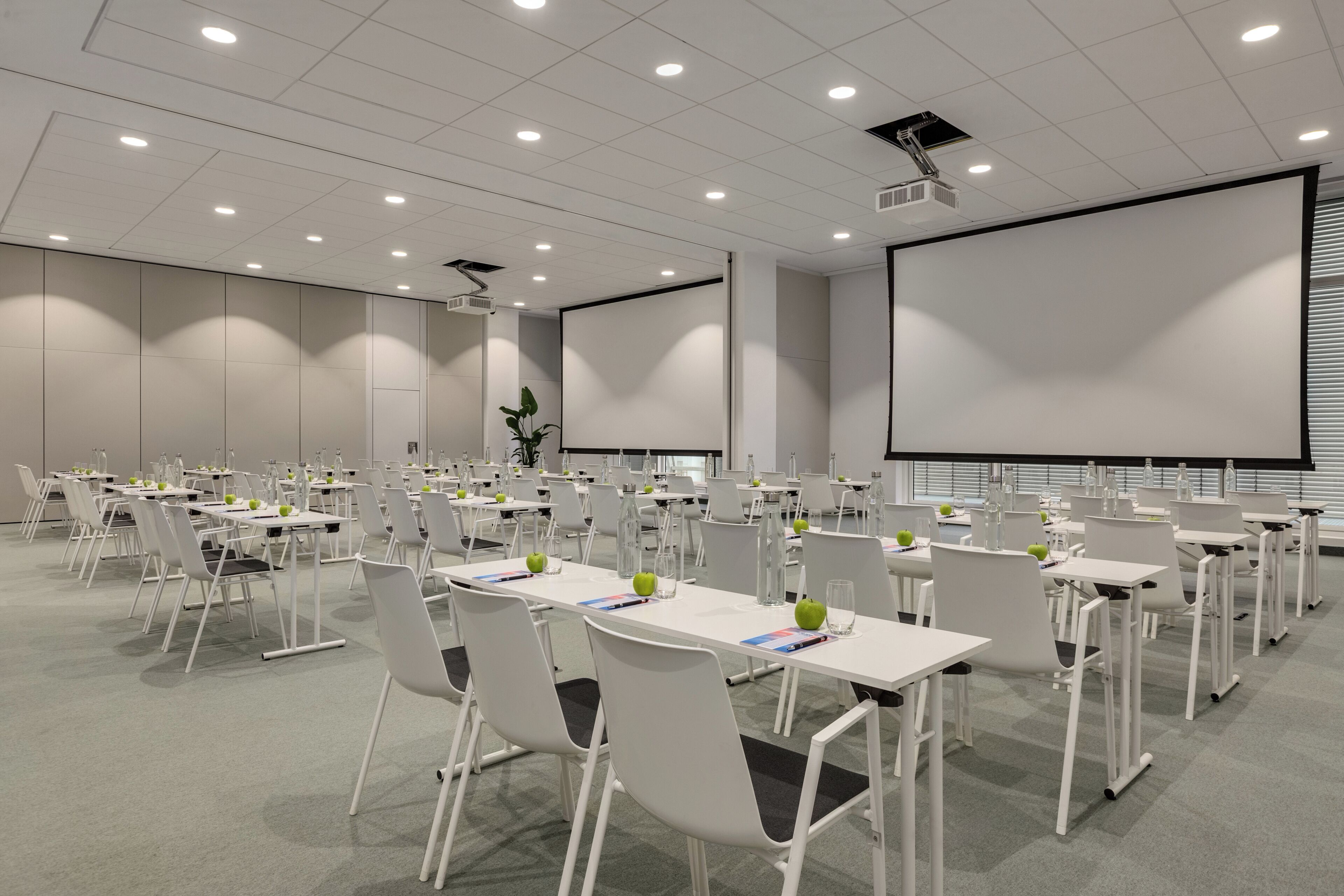 Une salle de conférence équipée de plusieurs tables, de chaises et d’un grand écran.