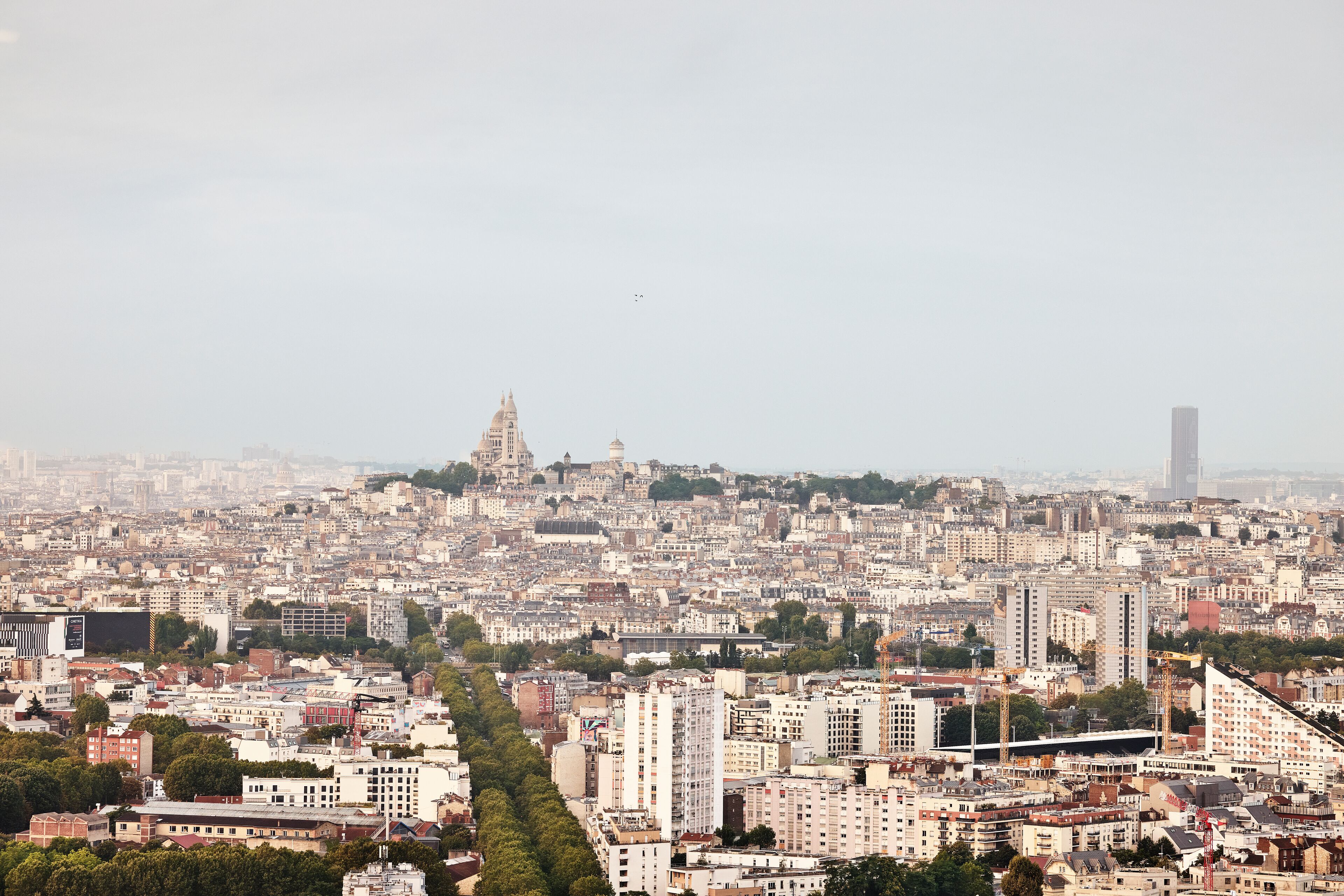 Une vue urbaine avec une tour imposante en arrière-plan, des bâtiments urbains denses et une vue dégagée sur l’agencement de la ville.