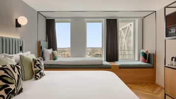 Una camera d'albergo moderna con un letto grande, un'area salotto con vista e un angolo cottura.