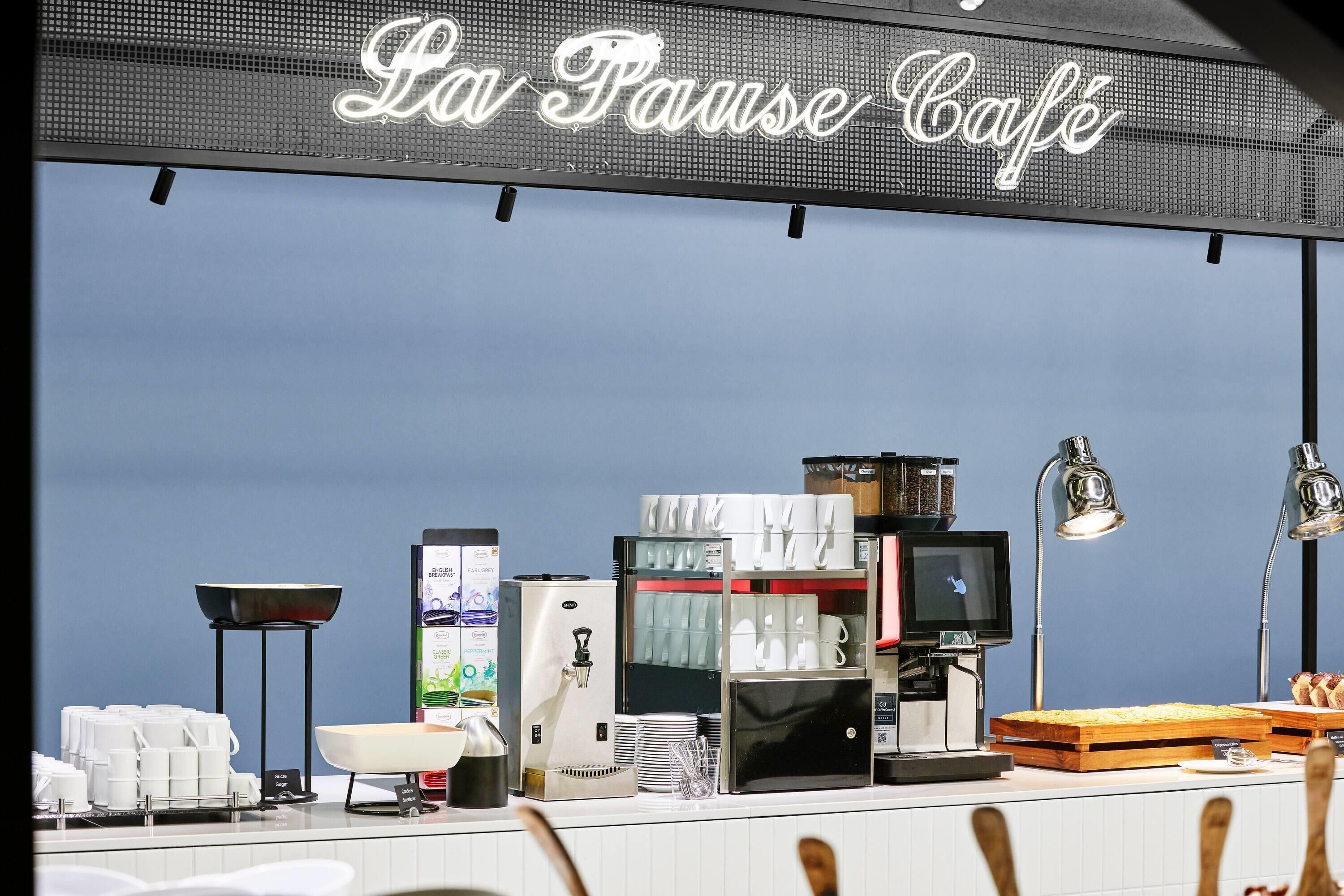 A café with a sign reading 'La Pause Café' and a coffee machine on display.