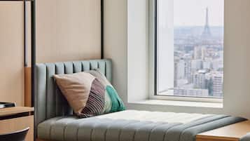 A modern room with a view of the Eiffel Tower, a cushioned bench, a wooden desk, and a window.