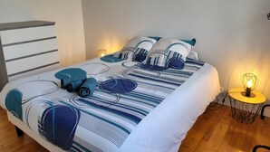 Un lit bien fait, avec une couvre-lit à rayures et des coussins assortis, deux lampes de chevet et un plancher en bois.