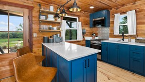 A modern kitchen with wooden walls, blue cabinets, and a central island. - The Hendo - Cabin #2- Intimate Family Getaway (Henderson)
