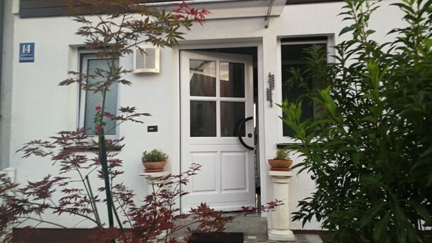 A white building with a number '14' sign, a white door, and potted plants. - München Waldperlach Ruhig und Großzügige Wohnung (München)