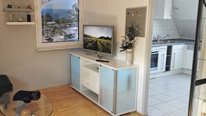 A compact living space with a balcony, a TV, a dining area, and a kitchen. - München Waldperlach Ruhig und Großzügige Wohnung (München)