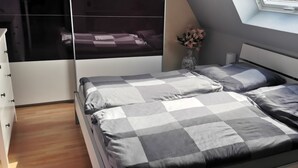 A bedroom with two beds, a large mirror, a window with a view, and a vase with flowers. - München Waldperlach Ruhig und Großzügige Wohnung (München)
