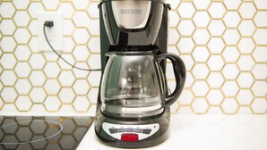 A coffee maker with a digital display and a timer, placed on a kitchen counter with a honeycomb-patterned backsplash. - Sunburst Inn The Beachside Suite - Room 5 (Indian Shores)