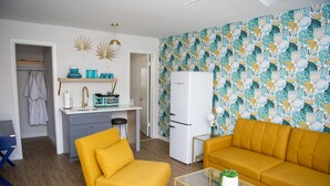 Um espaço de estar compacto com cozinha compacta, um sofá, uma mesa de centro e parede estampada.