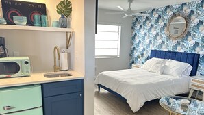 A compact bedroom with a bed, a small bedside table, a round glass table, and a microwave on the left. - Sunburst Inn The Beachside Classic - Room 4 (Indian Shores)