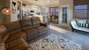Een moderne woonkamer met een leren hoekbank, een kamerkleed met patroon en een plafondventilator.