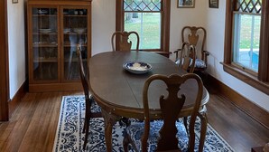 A dining room with a wooden table, chairs, a chandelier, and a cabinet with glass doors. - Historic 2 bedroom home in downtown Stevensville. Pet friendly! RV parking (Stevensville)