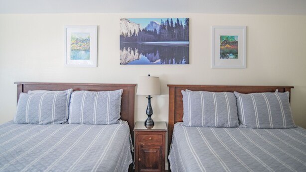 A bedroom with two beds, a nightstand with a lamp, and three framed pictures on the wall. - Mt Williamson Motel and Basecamp (Independence)