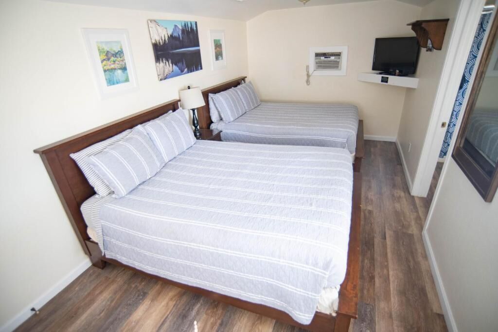 A bedroom with two beds, a TV, and artwork on the wall.