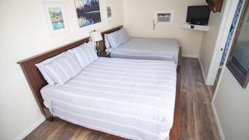 A bedroom with two beds, a TV, and artwork on the wall.