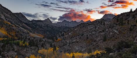 A mountainous landscape with autumn foliage and a sunset.