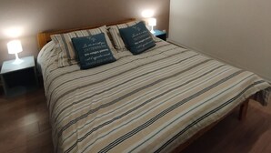 Un dormitorio con una cama, dos lámparas de noche, una lámpara de techo y un cuadro.