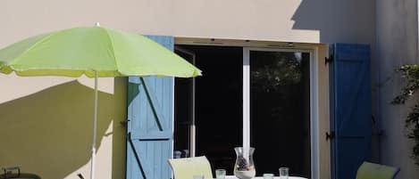 Un patio exterior con una mesa, sillas y una parrilla.