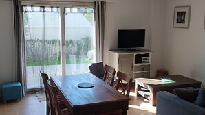 Un amplio salón con una mesa de comedor de madera, un sofá y un televisor.