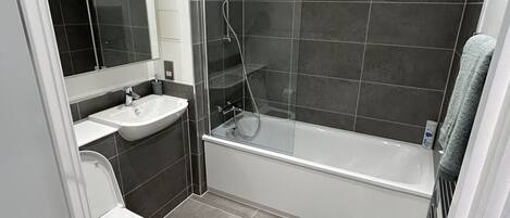 Ein modernes Badezimmer mit Toilette, Waschbecken und Badewanne.