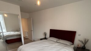 Un dormitorio con una cama grande, un espejo, una mesita de noche y una mesita auxiliar.