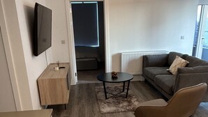 Una sala de estar moderna con un sofá, una mesa de centro y un televisor montado en la pared.