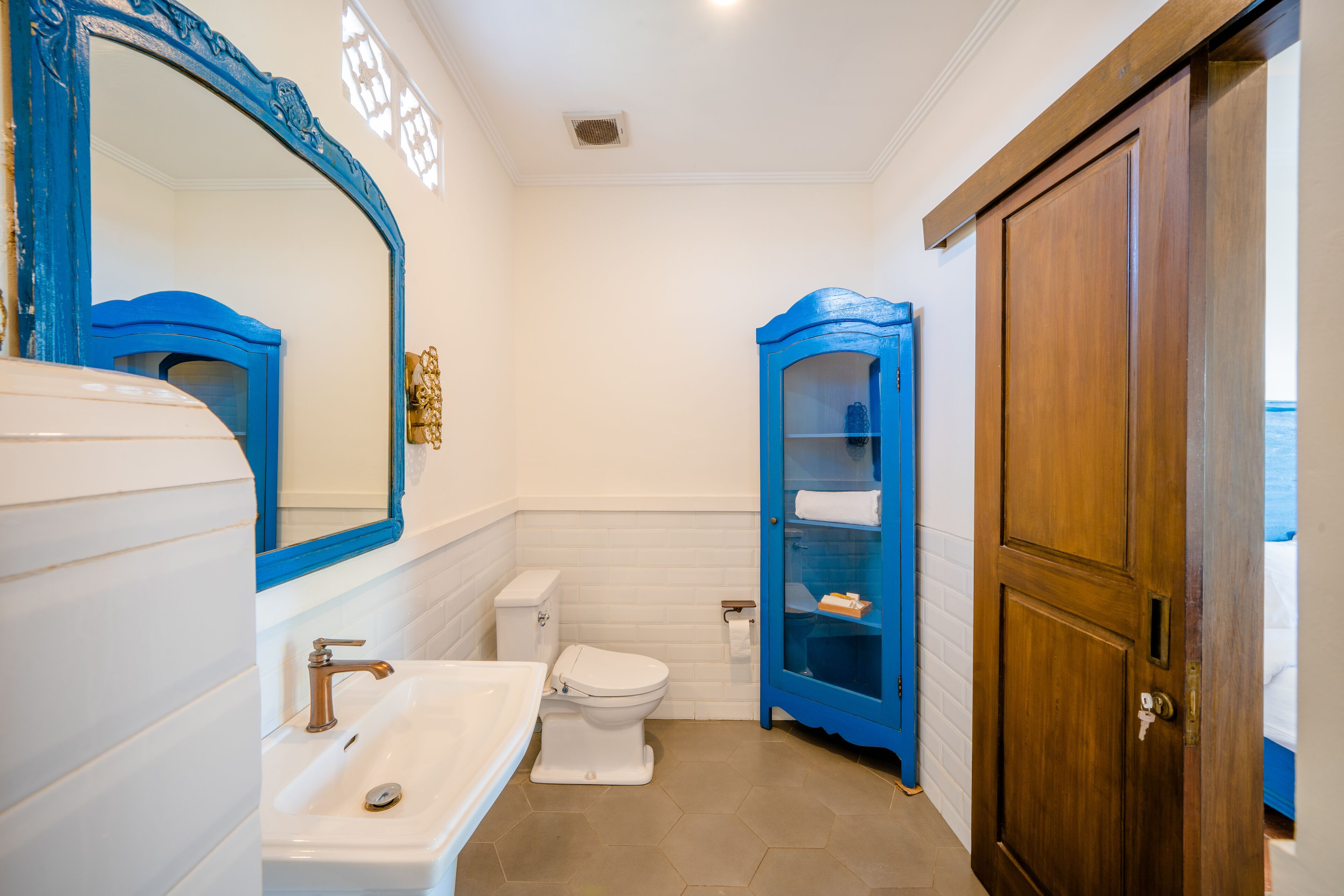 A bathroom with a white sink, a toilet, and a blue cabinet.