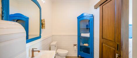 A bathroom with a white sink, a toilet, and a blue cabinet.