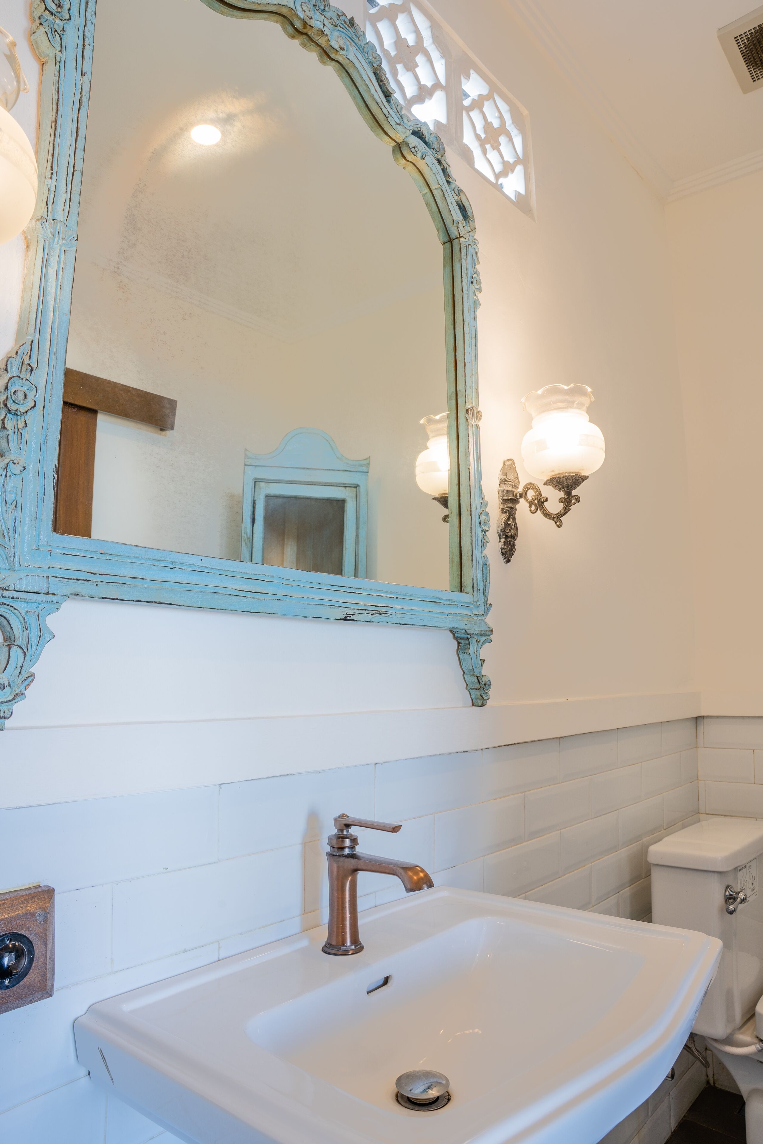 A bathroom with a white sink, a blue-framed mirror, and a toilet.