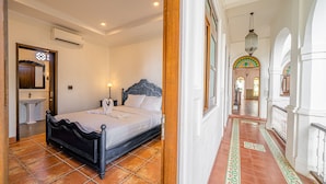 Un dormitorio con cama, mesita de noche y baño con lavabo y espejo.