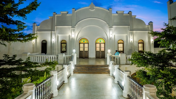 Un edificio imponente con un arco central, múltiples escaleras y una entrada bien iluminada.