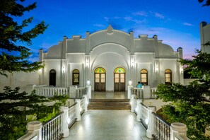 A grand building with a central archway, multiple staircases, and a well-lit entrance. - Pitaloka Hotel Sanur By DeWizZManagement (Denpasar)