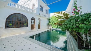 Un patio con piscina, edificios blancos y cielo azul.