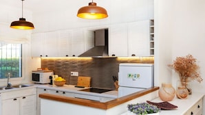 Una cocina moderna con armarios blancos, una isla central, un microondas y un refrigerador.