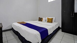 A bedroom with a bed, a window, and a wardrobe. - Hotel O Losmen Tjabe Merah Near Alfamart Bintaro (Purwokerto)