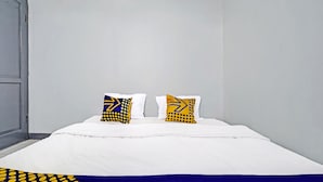A bed with white bedding and two pillows with geometric patterns. - Hotel O Losmen Tjabe Merah Near Alfamart Bintaro (Purwokerto)