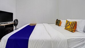 A hotel room with a bed, a TV, and a fan. - Hotel O Losmen Tjabe Merah Near Alfamart Bintaro (Purwokerto)