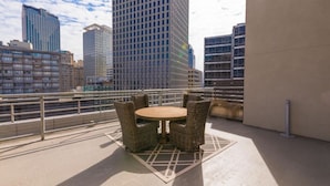 Ein Balkon mit Korbmöbeln und Blick auf Stadtgebäude.