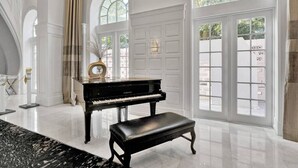 A grand piano in a spacious room with large windows and elegant white walls. - Cozy Beachfront 2 BDR Miami Beach Condo 406 (Miami Beach)