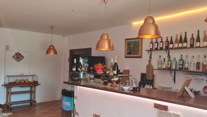 A bar area with copper pendant lights, shelves of wine bottles, and a variety of bar tools. - MoMa RoofGarden (San Polo Matese)
