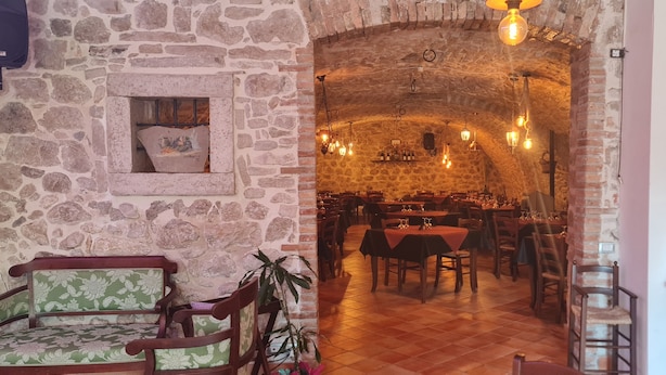 A stone-walled dining area with wooden furniture and hanging lights. - MoMa RoofGarden (San Polo Matese)