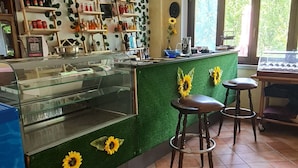 A cafe with a green counter, sunflower decorations, and tiled flooring. - MoMa RoofGarden (San Polo Matese)