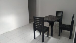 A dining area with a rectangular table and four black chairs. The room has white tiled flooring and white walls. - Hotel O Yellow White Guesthouse Palu (Palu)