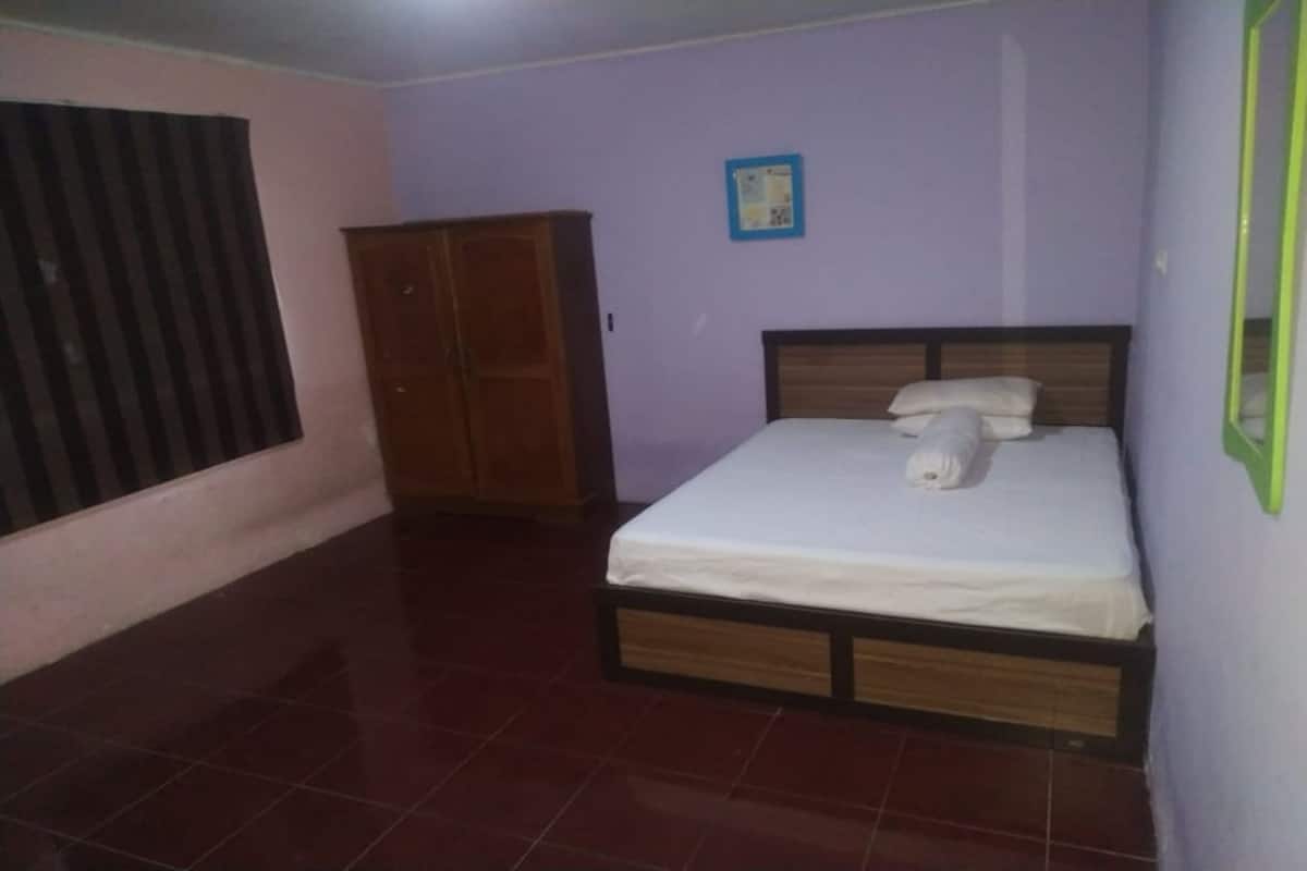 Une chambre à coucher avec un lit, une armoire et une fenêtre équipée de stores.