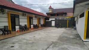 A courtyard with outdoor seating, a motorcycle, and a building with a sign reading "Yellow White guest house". - Hotel O Yellow White Guesthouse Palu (Palu)