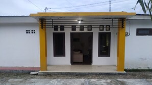 A building with a yellow and white exterior, a covered entrance with a bench, and a visible door. - Hotel O Yellow White Guesthouse Palu (Palu)
