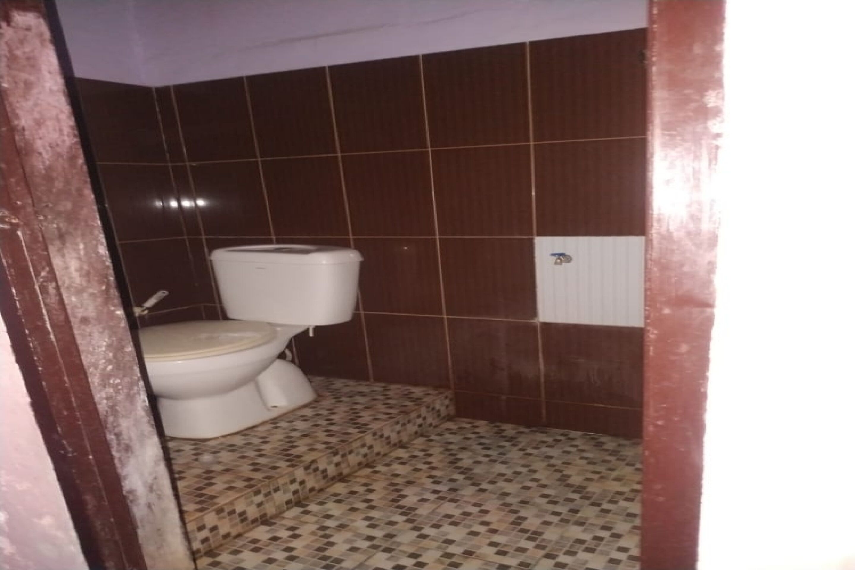 A small bathroom with a toilet, a sink, and tiled walls.