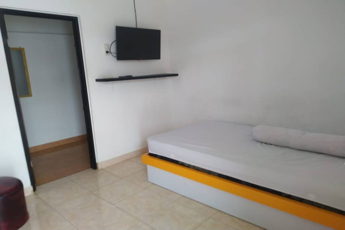 Une pièce avec un lit, un téléviseur fixé au mur et une porte.