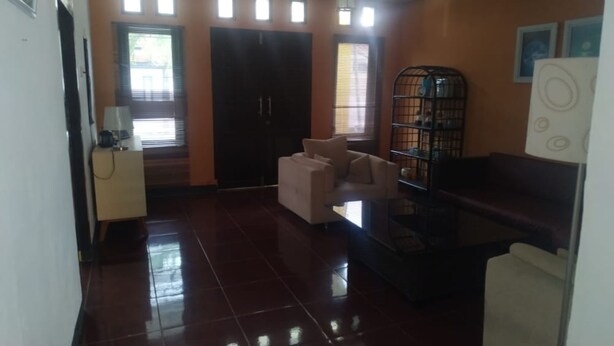 A room with a tiled floor, a sofa, a small table, a cabinet, and a bookshelf. - Hotel O Yellow White Guesthouse Palu (Palu)